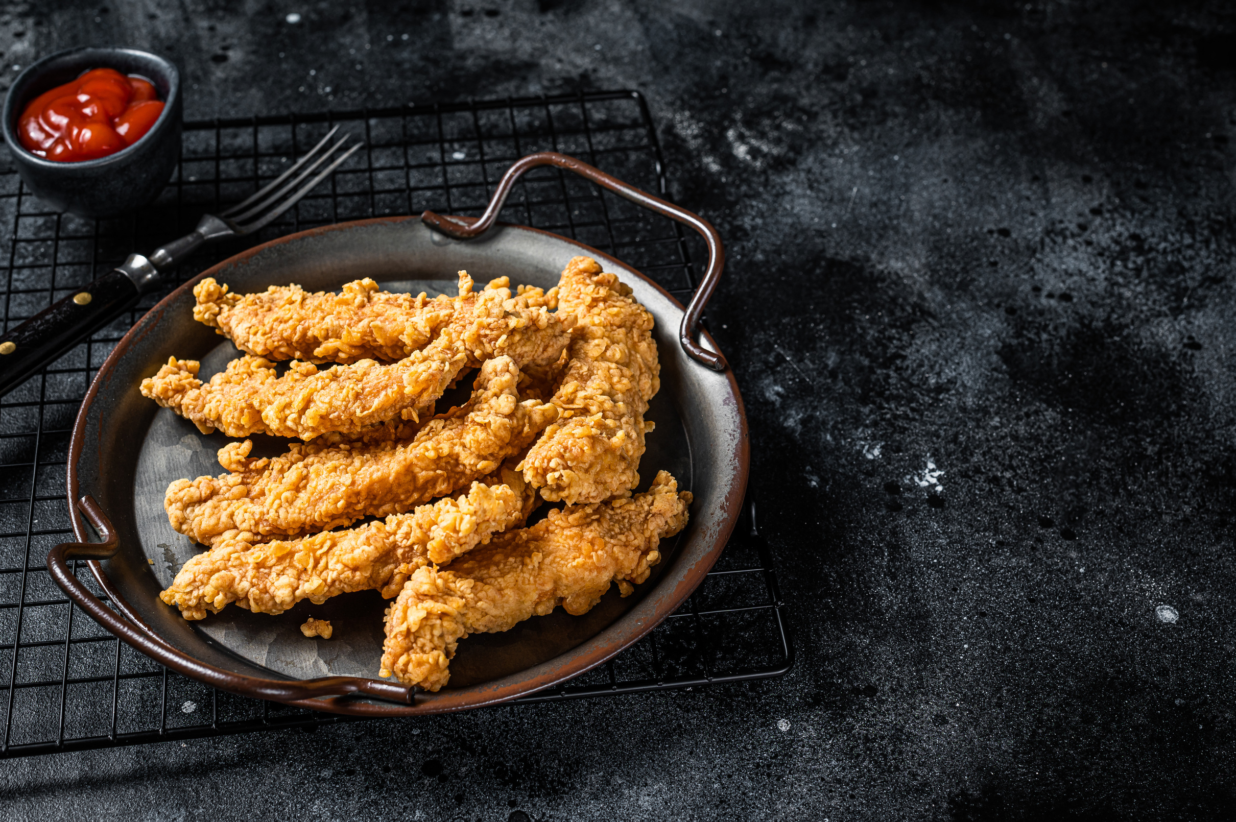 Crispy chicken tenders strips with Ketchup. Black background. To